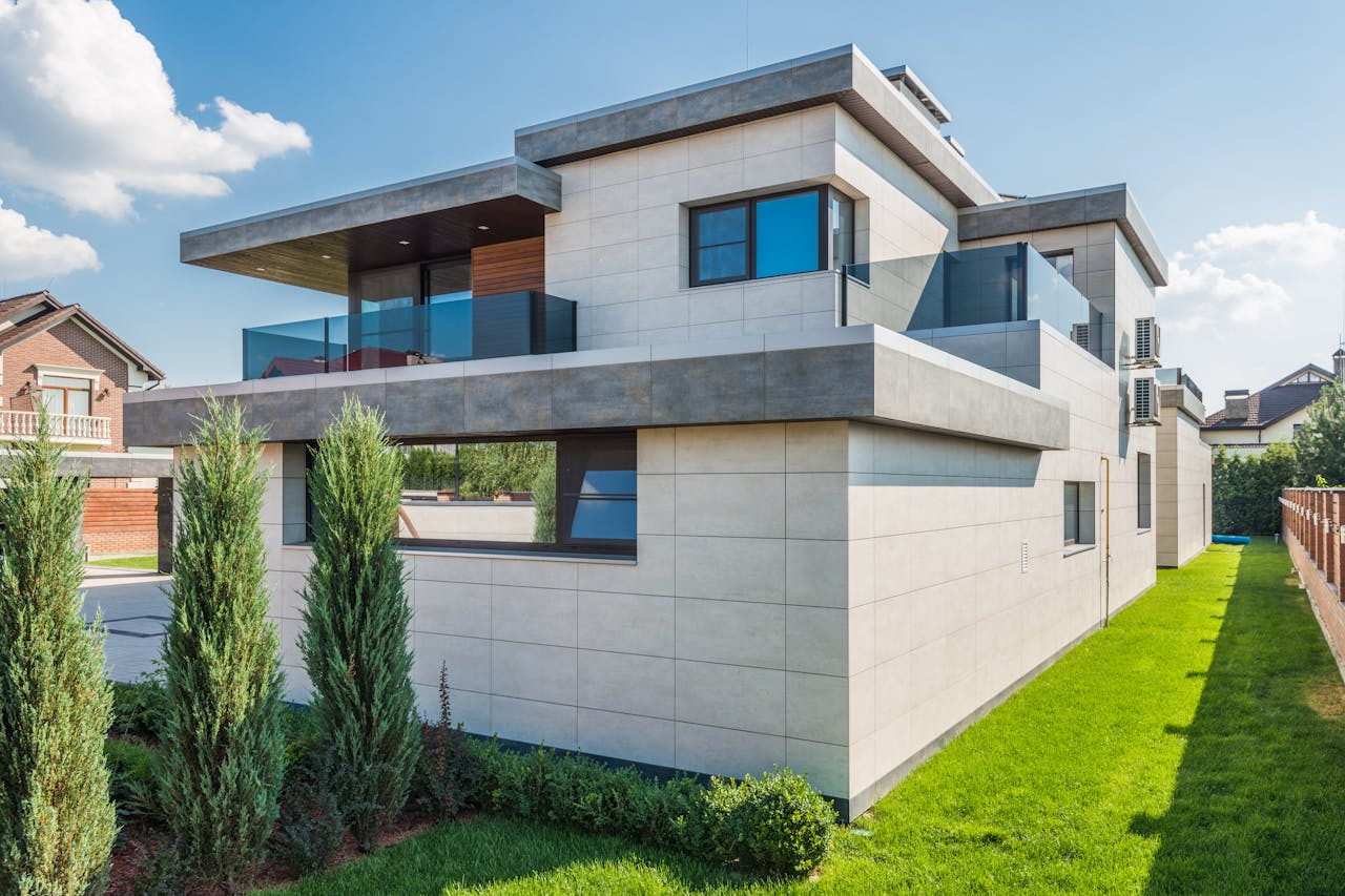 Contemporary two-story house with clean lines surrounded by green grass and blue sky.